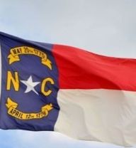 North Carolina state flag flying over cloudy blue sky